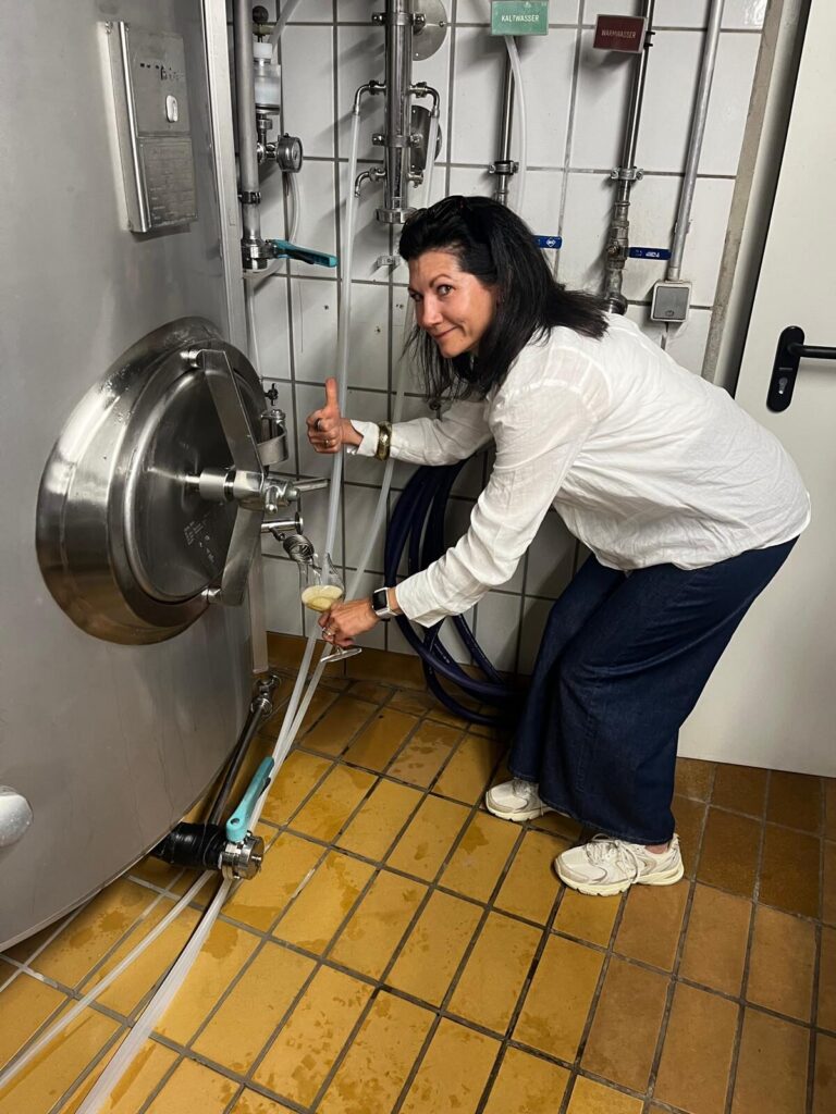 Frau zapft lächelnd Bier in einer Brauereianlage