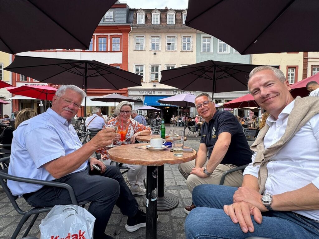 Vier Personen sitzen entspannt an einem Tisch in einem Straßencafé