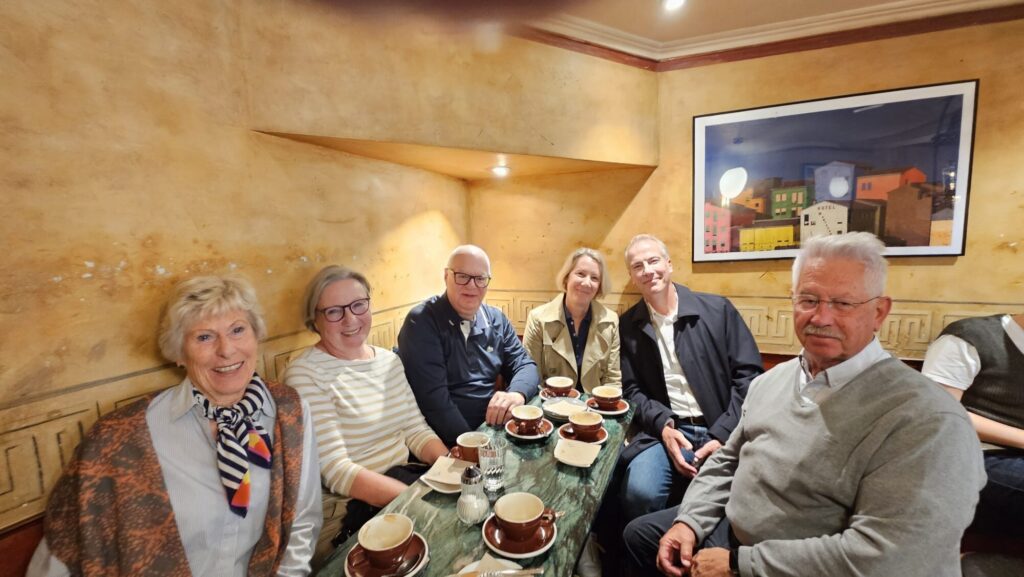 Sechs Personen treffen sich bei Kaffee in einem gemütlichen Café